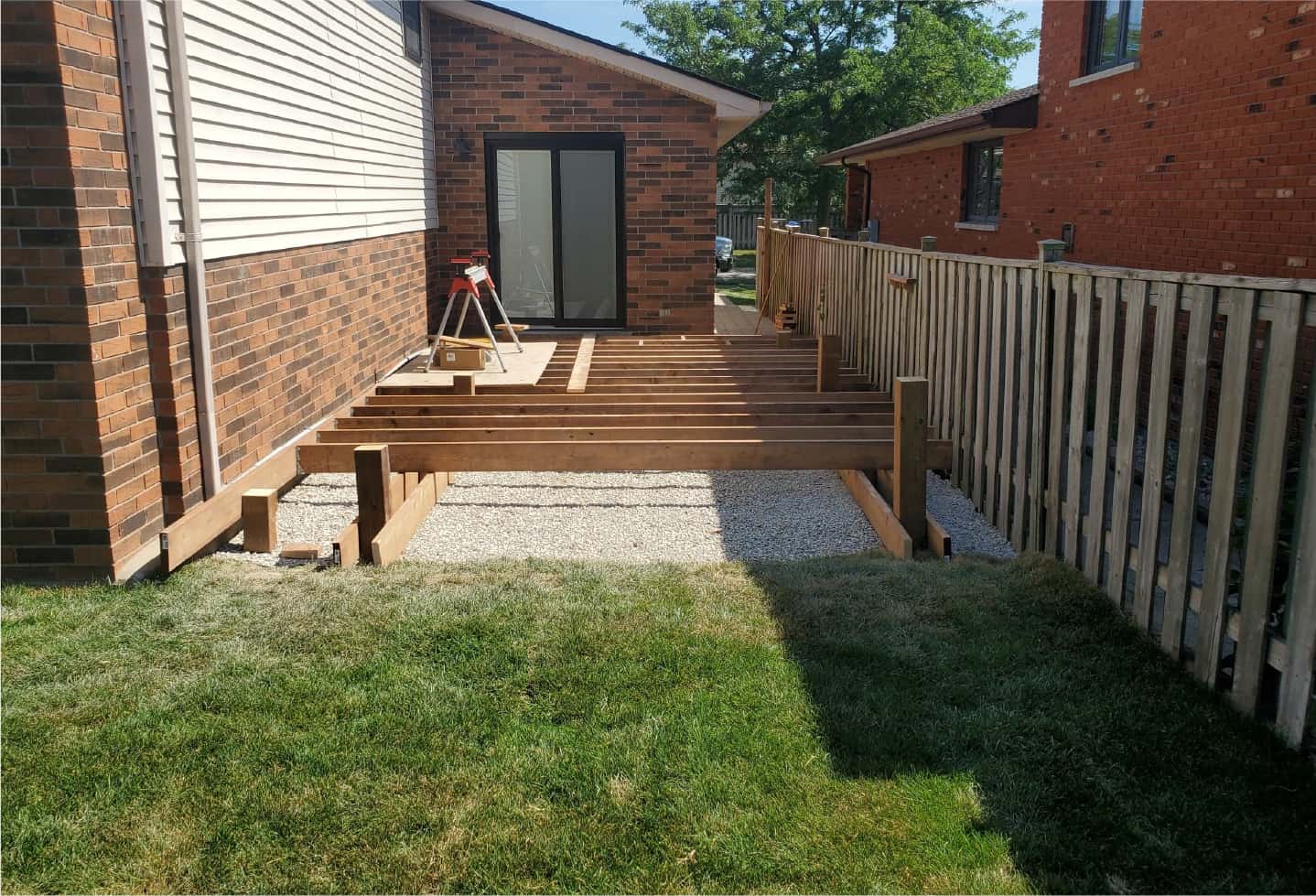 foundation of wood patio being installed in side yard with grass out front