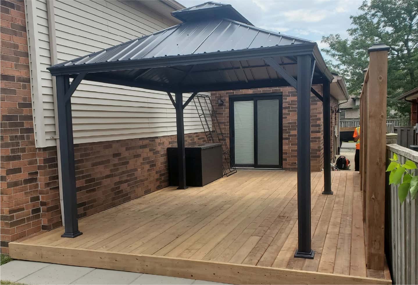 wood patio with black metal canopy newly installed with matching wood fence