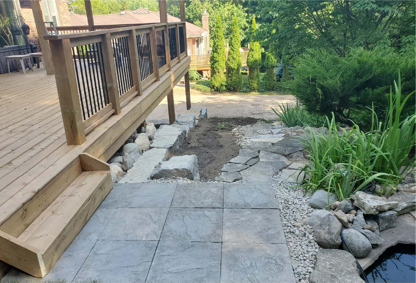 deck with steps and railing over looking a man made pond in backyard