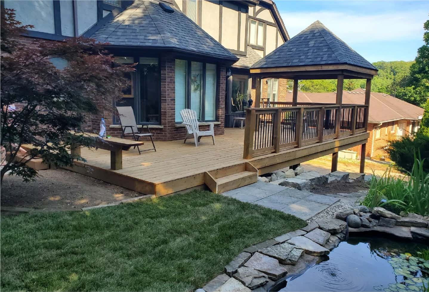 new wood deck over looking pond with gazebo and railing and bench and deck chairs