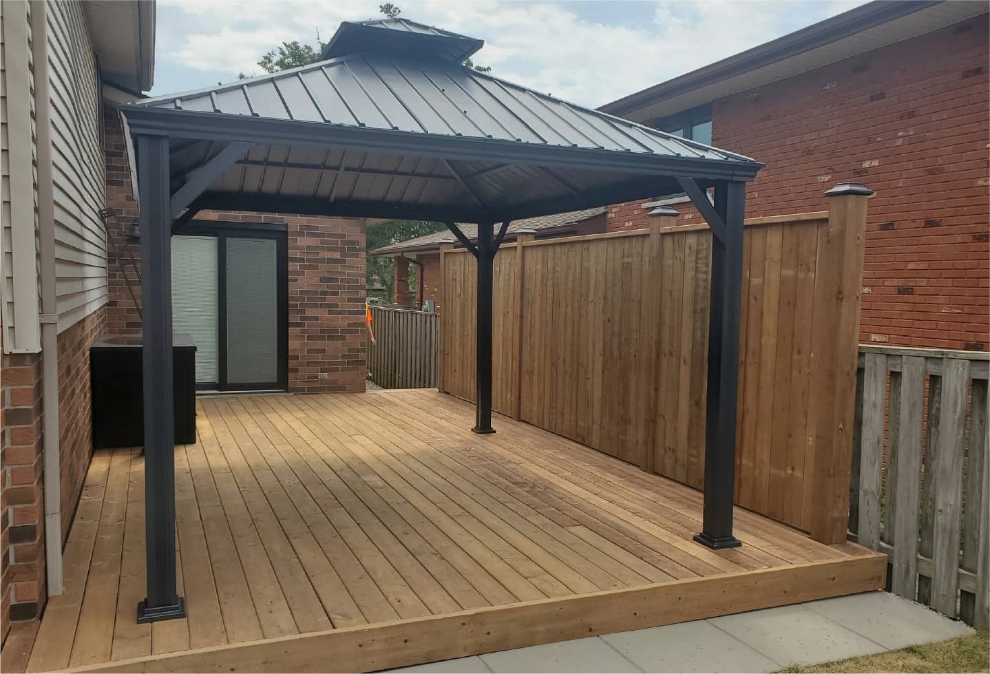 wood patio with black metal canopy newly installed with matching wood fence