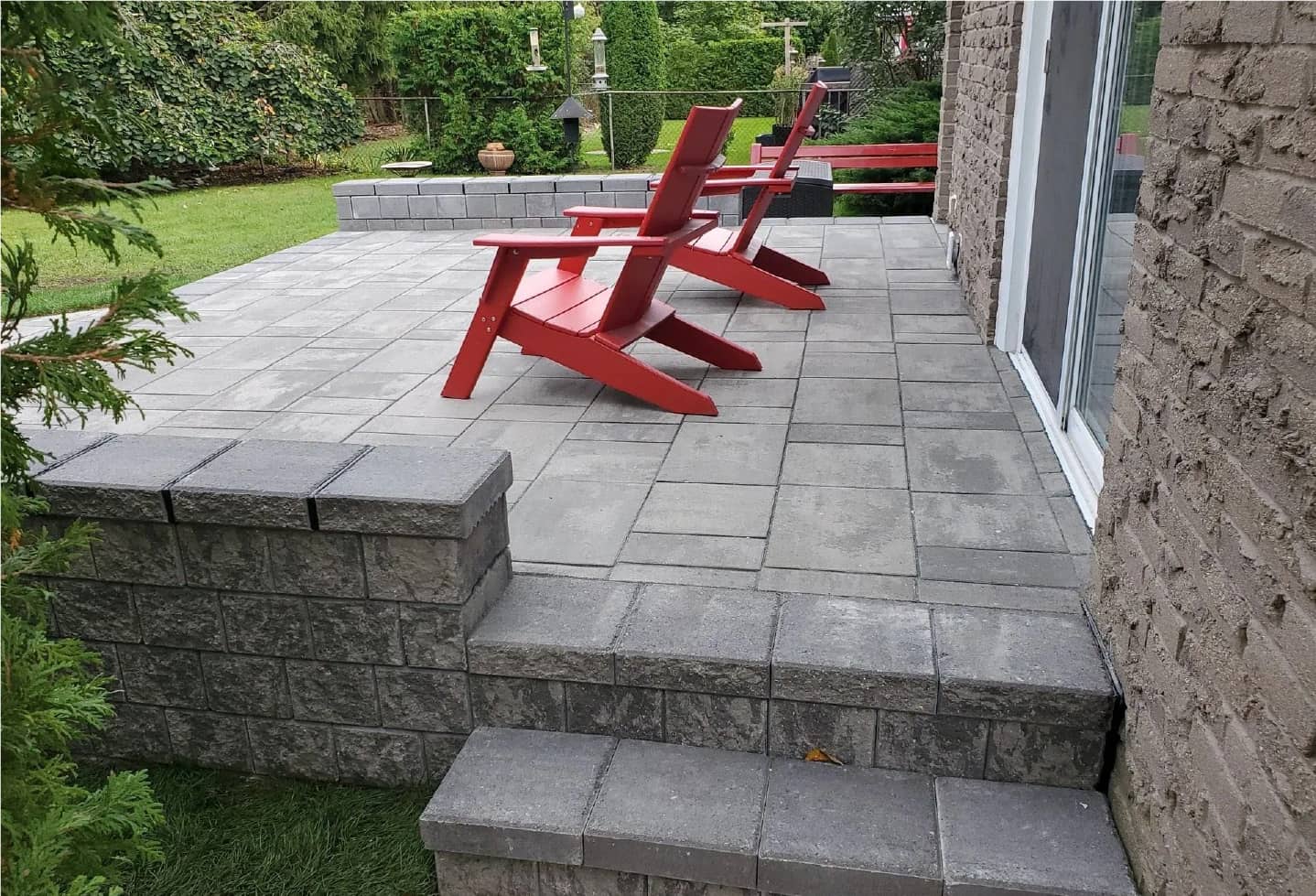 two red deck chairs on new stone patio backyard grass and patio door