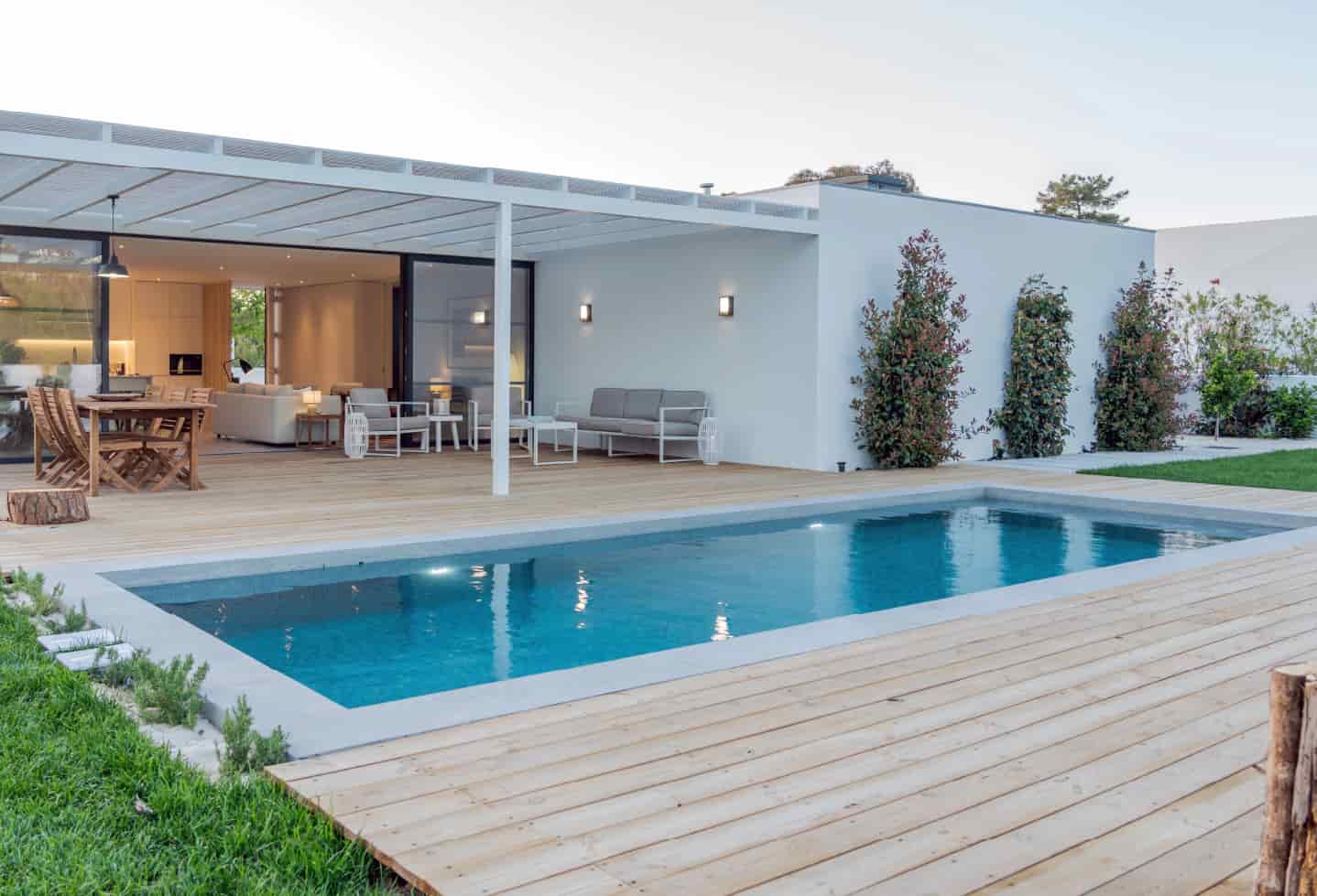 wood backyard patio with table and chairs next to swimming pool