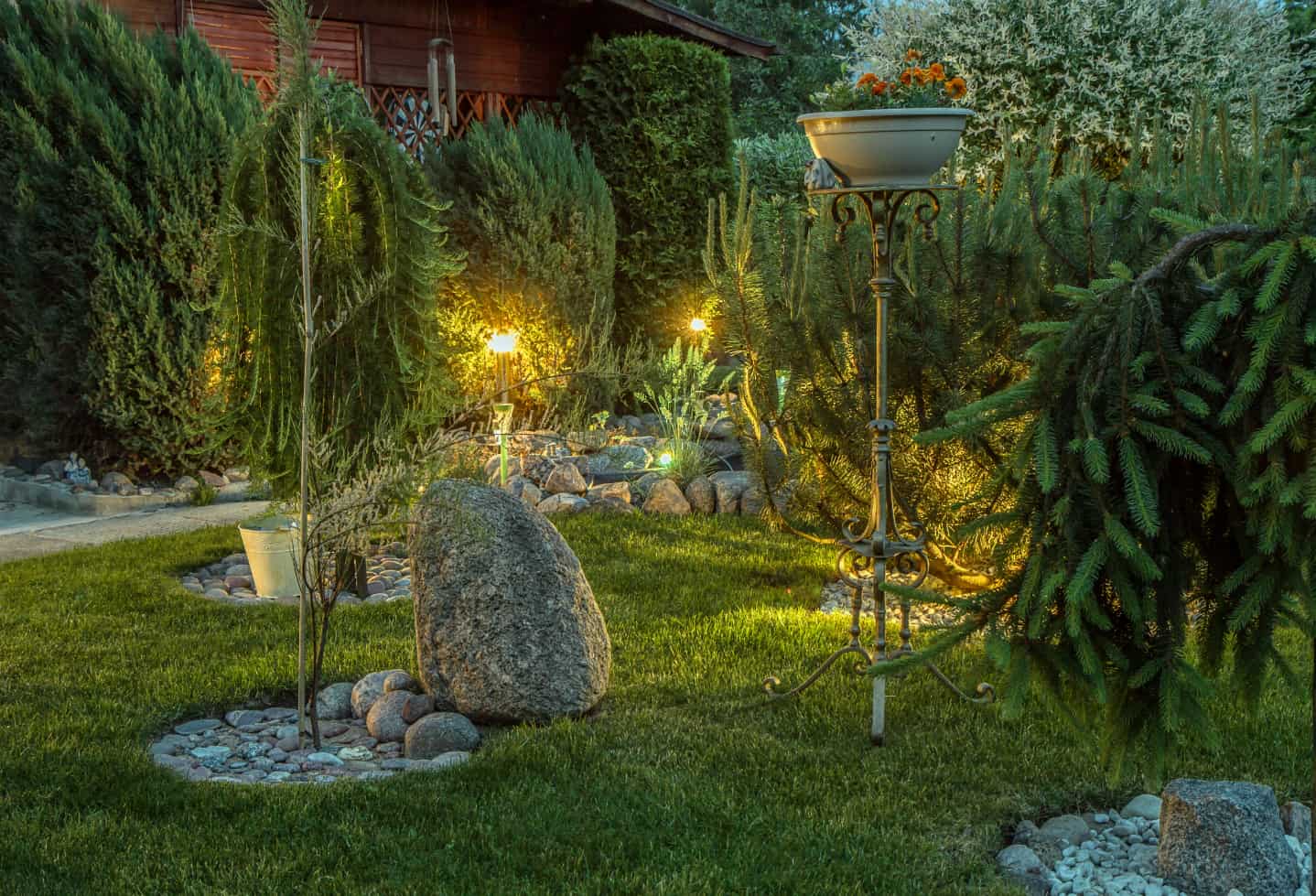 Backyard garden with lights on a night. rock features throughout