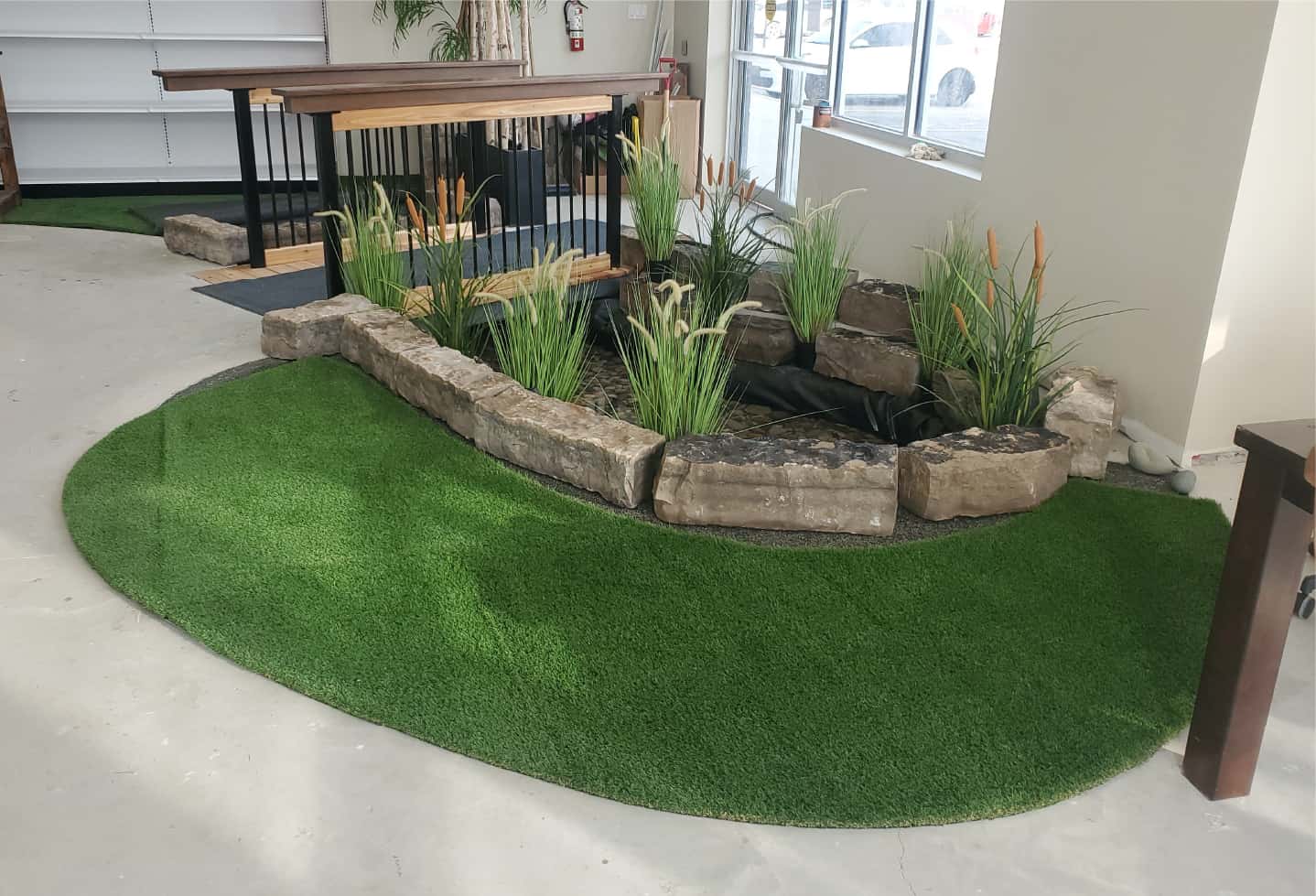 indoor pond in business with rock walls and artificial plant and artificial grass turf and bridge