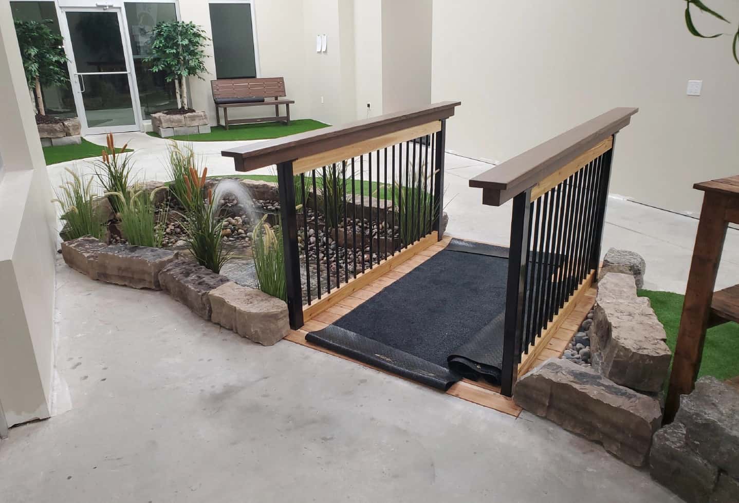 indoor pond in business with rock walls and artificial plant and artificial grass turf and bridge