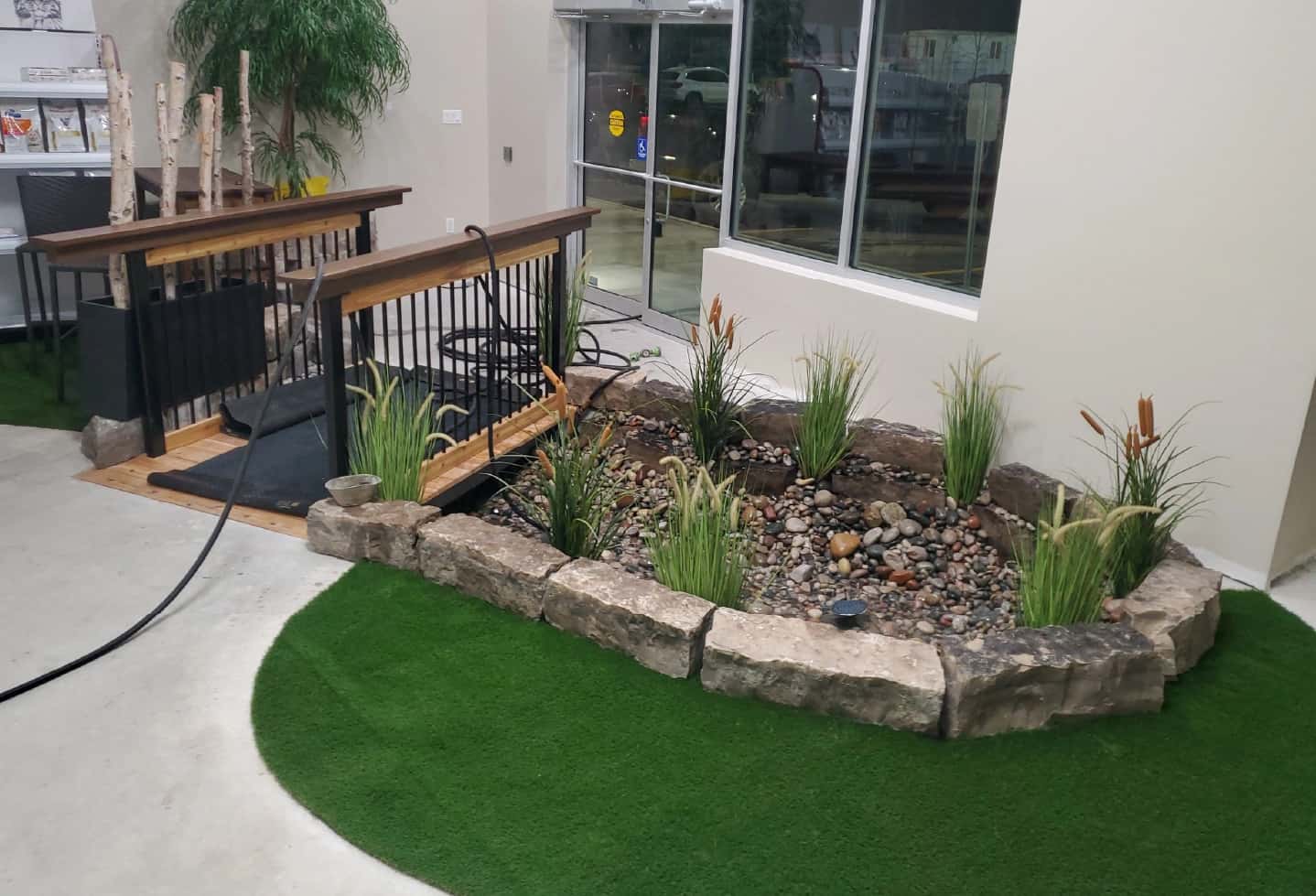 indoor pond in business with rock walls and artificial plant and artificial grass turf and bridge