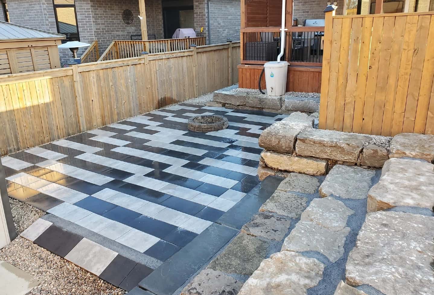 backyard black and stone tile patterned patio with grass in back with stone steps