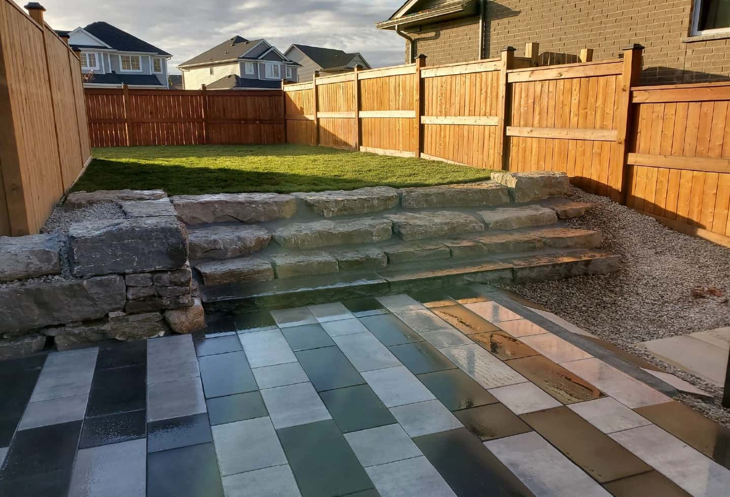 backyard black and stone tile patterned patio with grass in back with stone steps