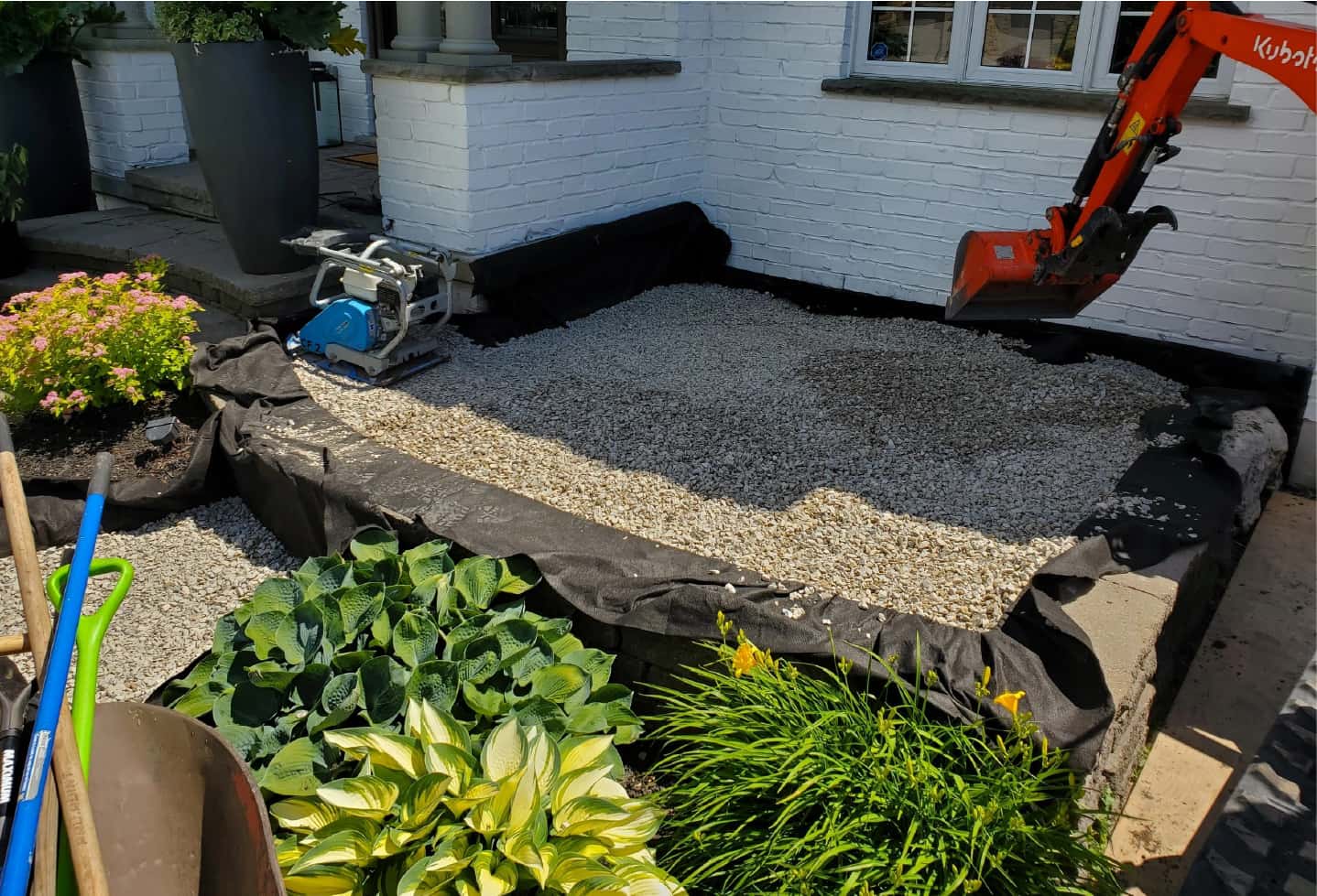 landscaping work on front yard of large house. with new hardscape installation mini patio step being done by excavator
