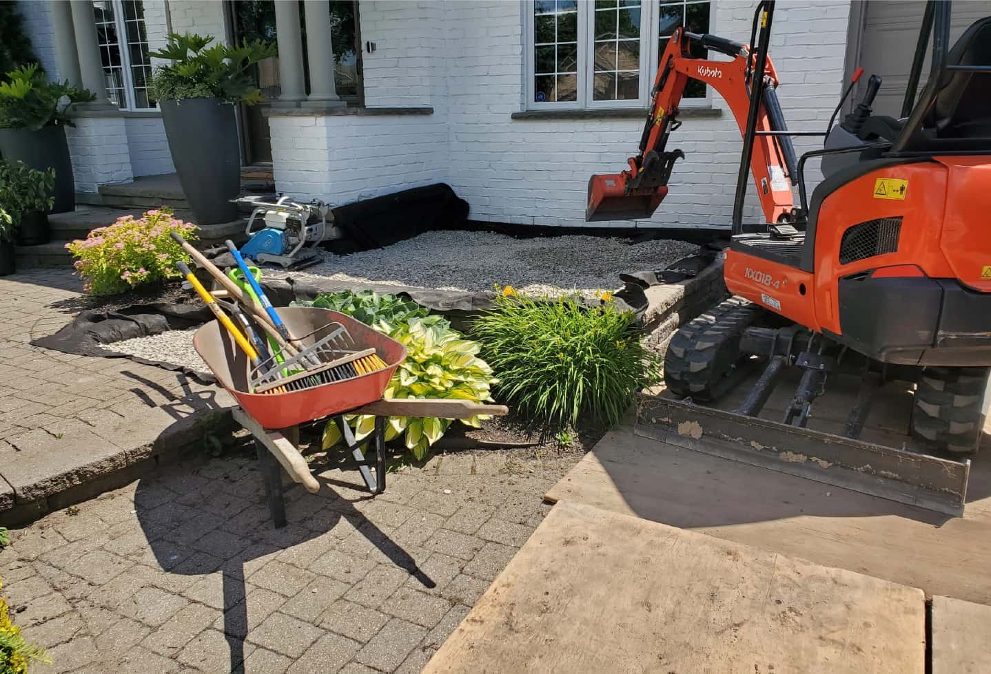 landscaping work on front yard of large house. with new hardscape installation being done by excavator