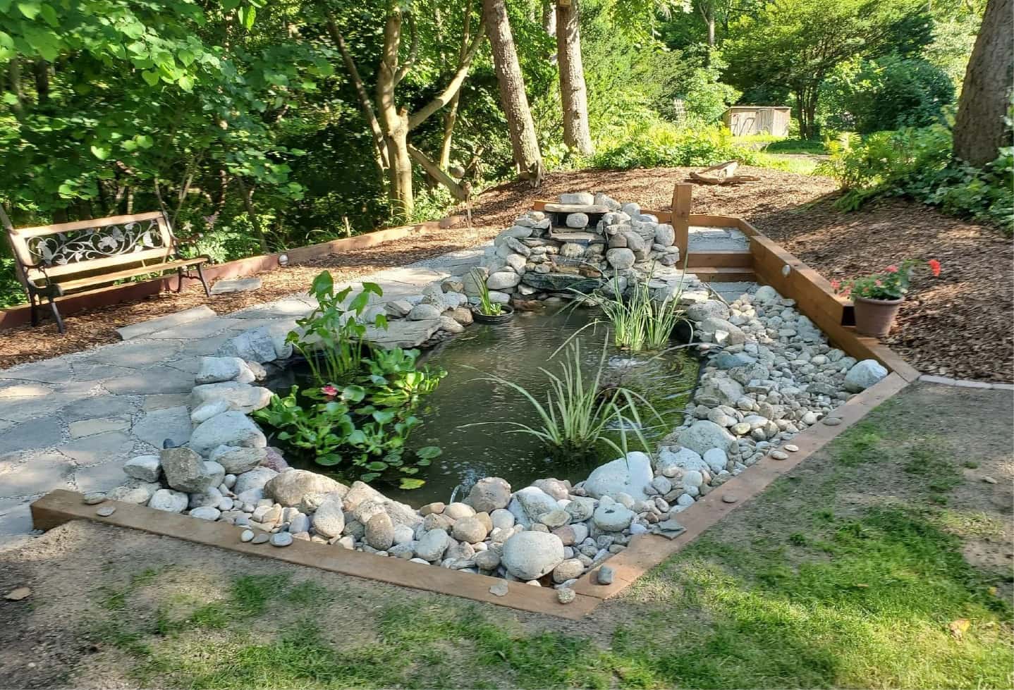 restored pond with rock surround and small waterfall in backyard