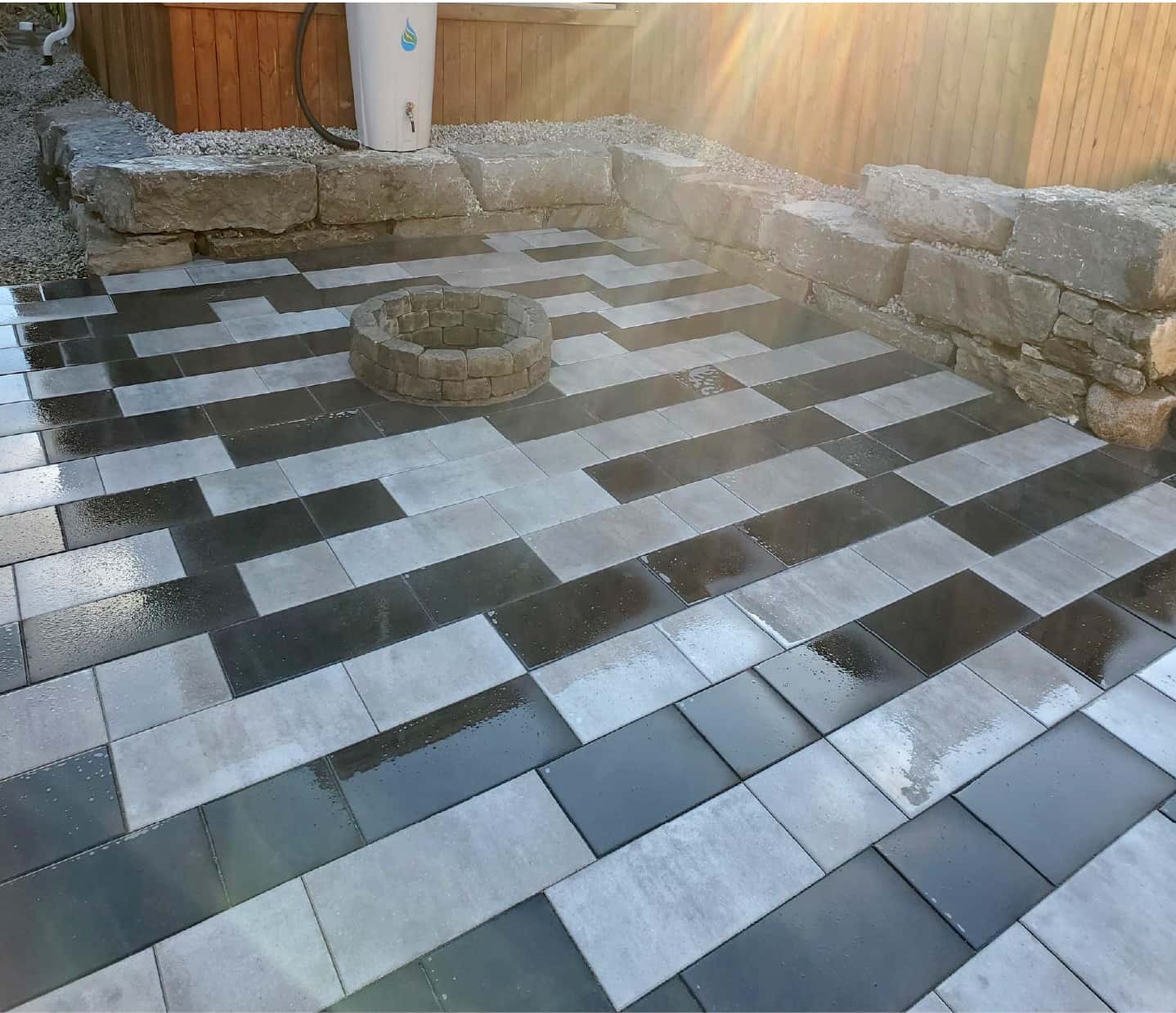 backyard black and stone tile patterned patio with grass in back with stone steps