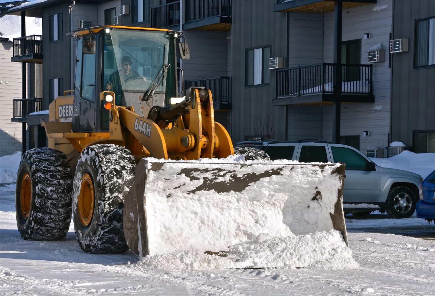 snow plow outside snowy day next to condo building
