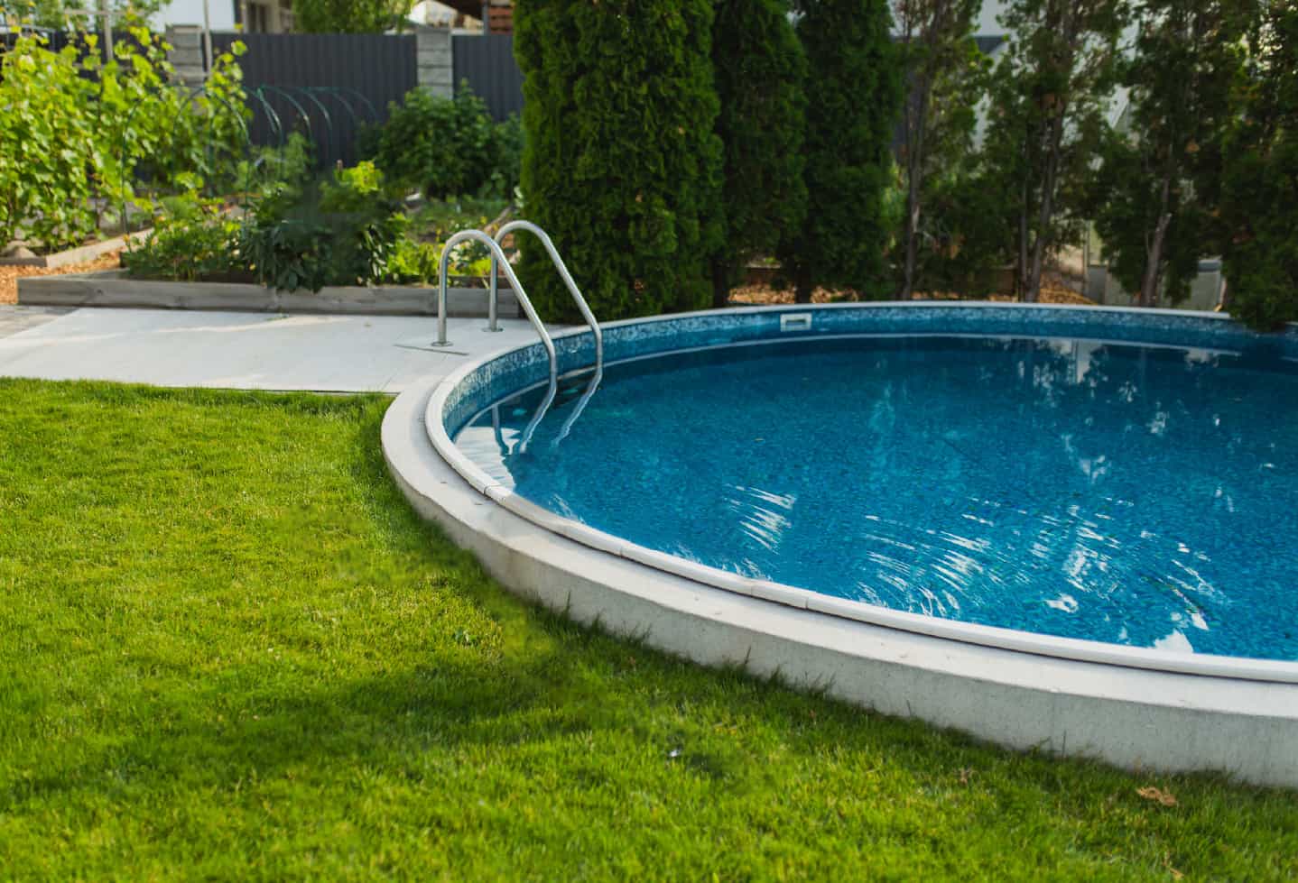 backyard concrete and blue tiled inground pool with grass lot