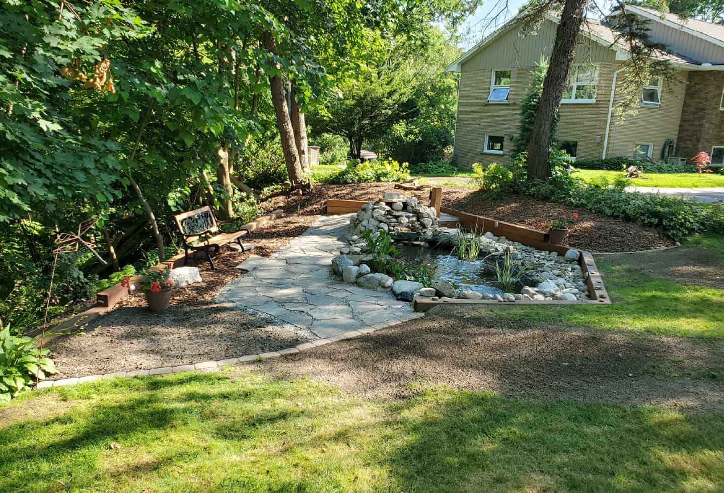 backyard outdoor installation of small pond with rock surround and small waterfall